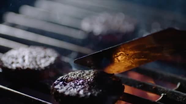 Close up of burger chops on grill with fire flames, chef turns them over, slow motion — Stock Video