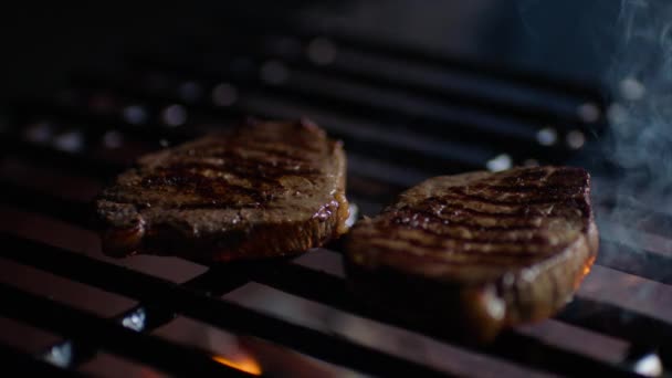 Close up de bifes na grelha com chamas de fogo, chef vira-los, câmera lenta — Vídeo de Stock