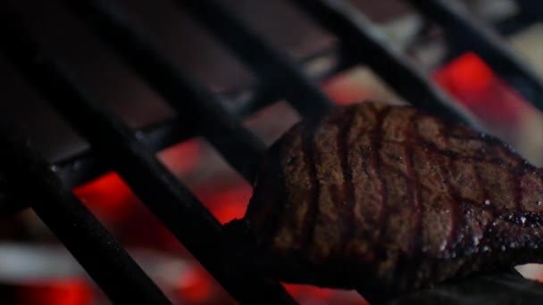 Крупный план стейков на гриле с огненным пламенем, шеф-повар переворачивает их, замедленное движение — стоковое видео