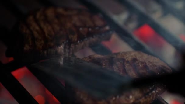 Close-up van steaks op grill met brand vlammen, chef-kok blijkt ze over, slow-motion — Stockvideo