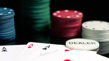 Siyah ayna yüzeyinde Poker fişleri ve as kartları