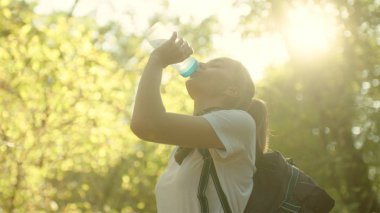 Genç güzel kız içme suyu güneş ışığı'da yürüyüş üzerinde