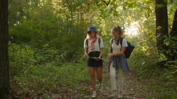 Лучшие друзья молодые женщины походы вместе с рюкзаками и карта в национальном парке — стоковое видео