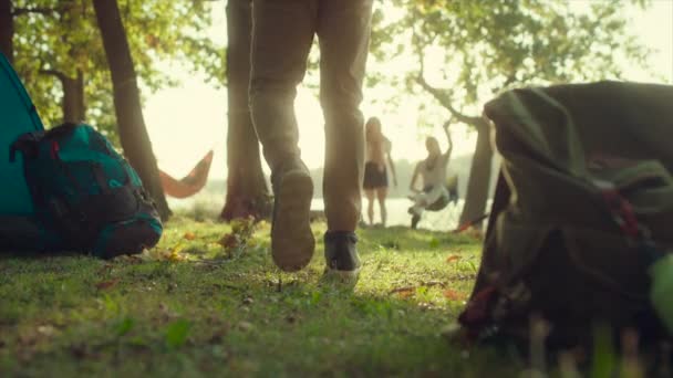 Mochilero uniéndose a sus amigos en el campamento. Hoguera y lago en el fondo — Vídeos de Stock