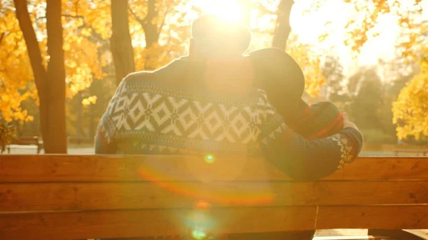 Casal sênior desfrutando do pôr do sol no banco no parque de outono — Fotografia de Stock