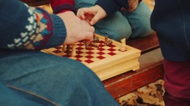 Küçük çocuklar, sonbahar parkta bankta, Büyükbaba ile satranç oynuyorlar