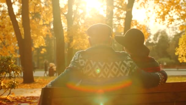Starší pár, kteří požívají západ slunce na lavičce v podzimní park — Stock video