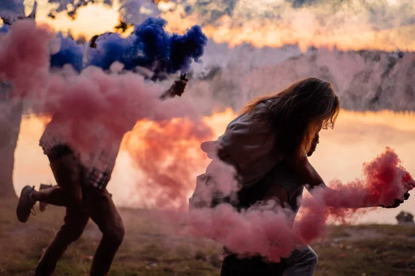 Grupo de amigos se divertindo com brilhos fumegantes de cor ao pôr do sol — Fotografia de Stock