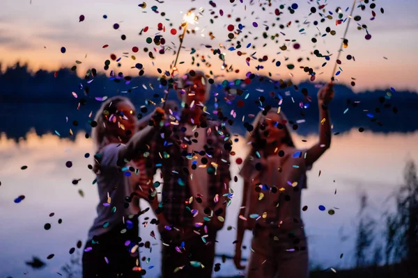 Amigos celebrando fiesta nocturna con bengalas y confeti —  Fotos de Stock
