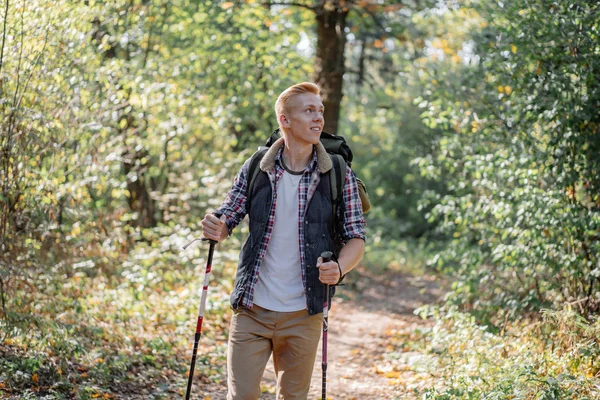 Fiatal férfi élvezi túrázás egyedül a nordic walking botok az erdő — Stock Fotó