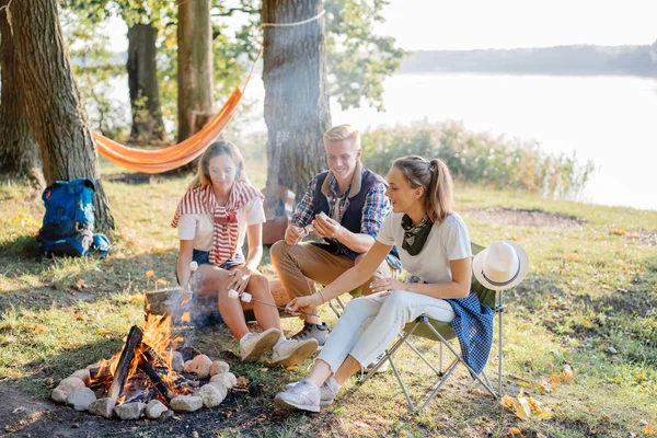 Yaz tatillerini üzerinde Marshmallows ateşin ortasına zammı yakın göl üzerinde yemek arkadaşlarım. Arka plan üzerinde kamp