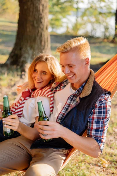 Young couple having fun outdoors with bottles of beer in their hands