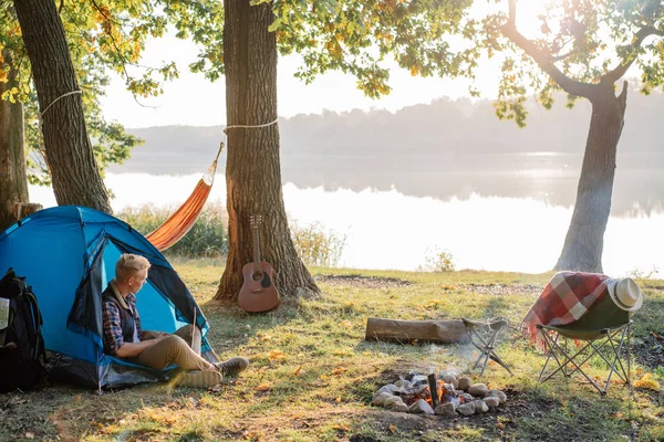 Gölde yürüyüş sırasında bir dizüstü bilgisayar üzerinde çalışan genç adam