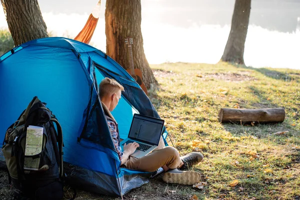 Dağ'da yürüyüş üzerinde dizüstü bilgisayar kullanan genç adam