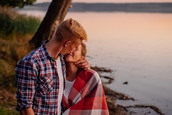 Jovem lindo casal beijando ao pôr do sol no lago — Fotografia de Stock