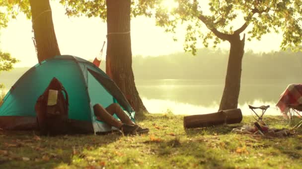 Camping al atardecer. Caminante está durmiendo en su tienda cerca de la hoguera — Vídeos de Stock