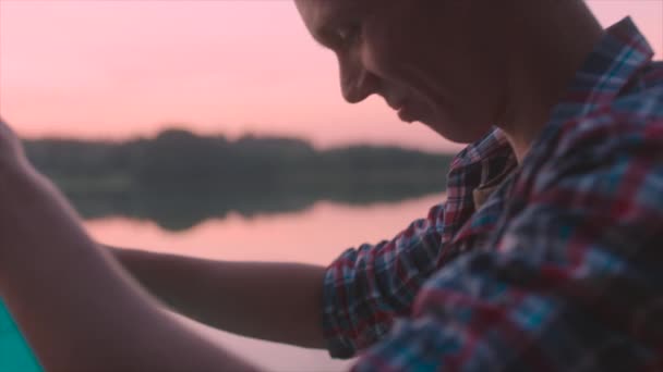 Casal jovem está iluminando a lanterna do céu ao pôr do sol — Vídeo de Stock