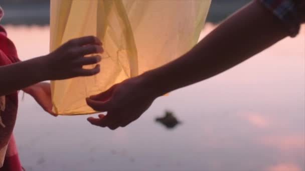 Lanterna Sky é lançado pelo jovem casal ao pôr do sol — Vídeo de Stock