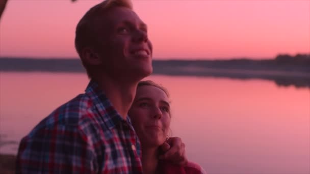 Os amantes se beijando ao pôr do sol no lago — Vídeo de Stock
