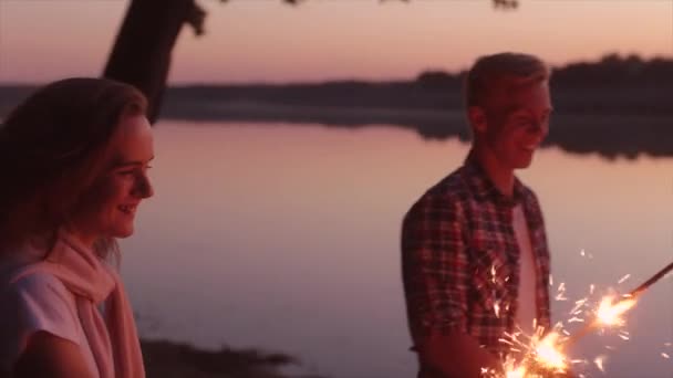 Amigos felices celebrando con destellos al atardecer — Vídeo de stock