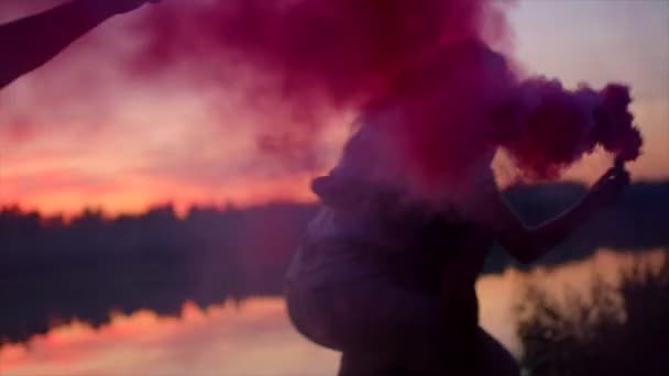 Mejores amigos tonteando con fuego de color ahumado al atardecer — Vídeos de Stock