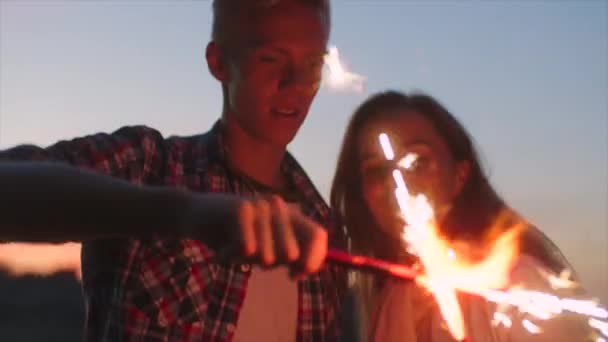 Tonåringar leker med gnistrar i solnedgången — Stockvideo