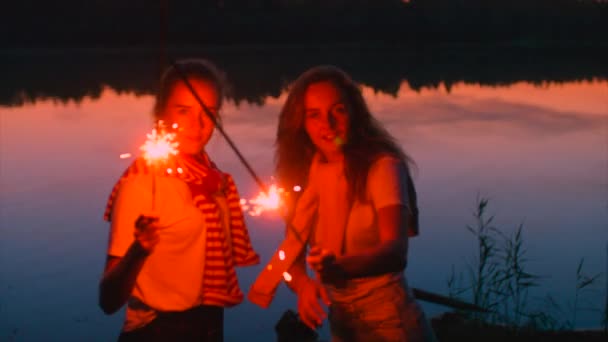 Две молодые женщины с блестками в руках ночью — стоковое видео
