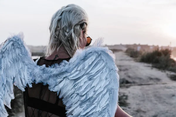 Backshot młoda kobieta z anielskimi skrzydłami o zachodzie słońca — Zdjęcie stockowe