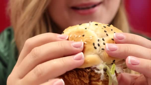 Крупним планом смачно смажений курячий бургер і красива жінка на фоні — стокове відео
