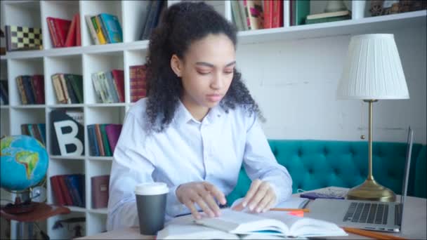 Vrouwelijke student een notitie maken terwijl de voorbereiding van de examens in de Universiteitsbibliotheek — Stockvideo