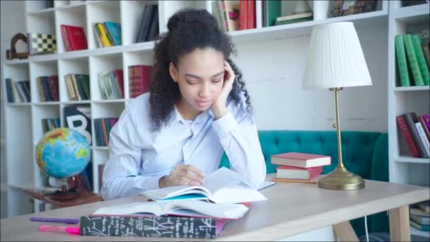 Retrato de una hermosa estudiante afroamericana leyendo libros de texto en la biblioteca del campus — Vídeo de stock