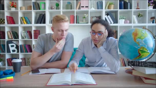여자 학생을 읽고 남자 학생을 돕는 라이브러리에 시험을 위해 그는 휴대 전화로 전환 — 비디오