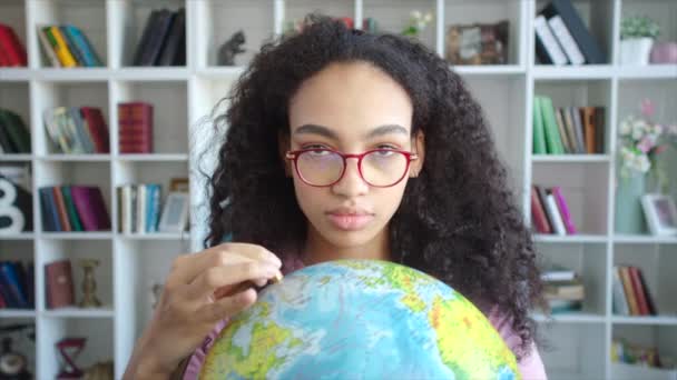 Молодая красивая африканская американка выбирает маршрут отпуска, висит на глобусе в руках — стоковое видео