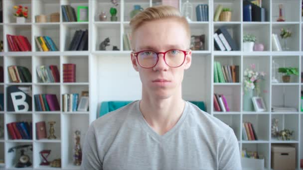 Junge Blondine mit Brille. Regale mit Büchern im Hintergrund — Stockvideo