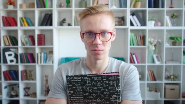 Retrato de estudante com óculos e livros didáticos em suas mãos no campus universitário — Vídeo de Stock