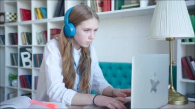 Kütüphanedeki laptop kullanarak sınav için hazırlanıyor güzel genç kız, kulaklıklar giyiyor