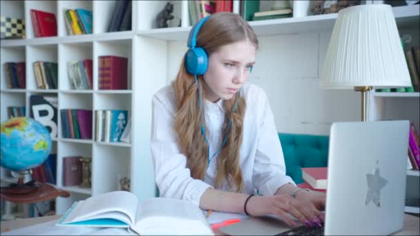 Red Hair student przygotowuje się do wejścia uniwersyteckiego za pomocą laptopa w bibliotece, noszenie słuchawek — Wideo stockowe