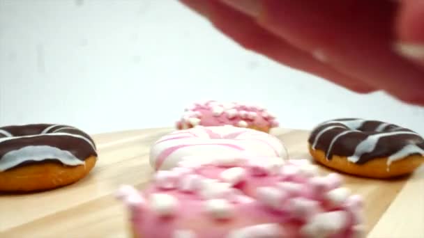 Tiro comercial de saboroso donut vitrificado na mão, donuts definidos no fundo — Vídeo de Stock