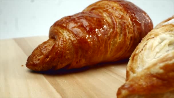 Croissants azúcar en polvo sobre la mesa, fondo blanco — Vídeo de stock