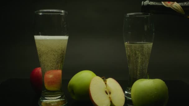 Giet cider in de glazen en verse appels om de zwarte achtergrond — Stockvideo