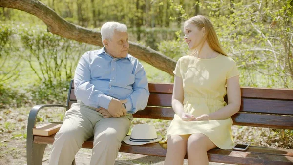 El viejo y su nieta están teniendo una charla en el parque el día de verano. Imágenes De Stock Sin Royalties Gratis