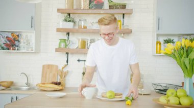 Güzel sarışın adam mutfakta sabah kız arkadaşı için kahvaltı yapıyor