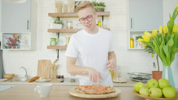 Genç adam pizza yiyor ve mutfakta DJ diski gibi çalıyor. — Stok video