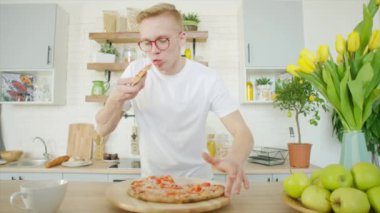 Genç adam evde İtalyan pizzasının tadını çıkarıyor.