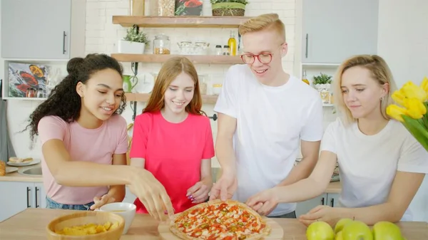 Szczęśliwi przyjaciele jedzą pizzę w kuchni Obraz Stockowy