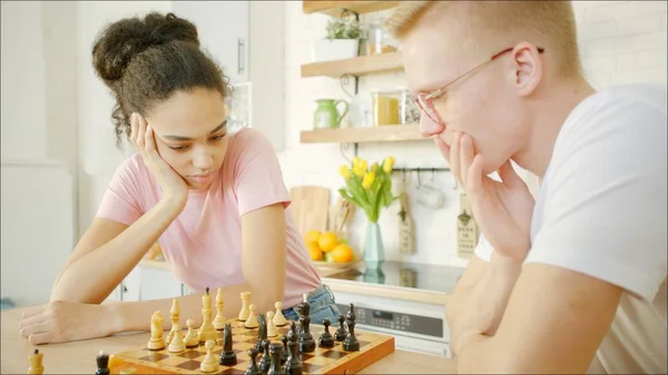 A fiatal afro-amerikai nő sakkozik a szőke férfival. Stock Kép