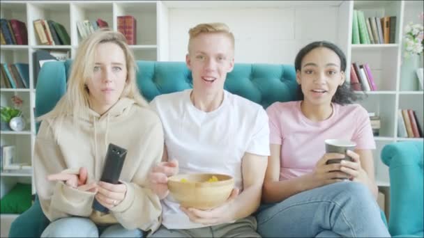 Οι φίλοι παρακολουθούν ποδόσφαιρο στην τηλεόραση και τρώνε σνακ στον καναπέ — Αρχείο Βίντεο