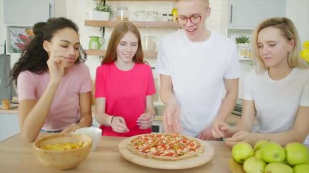 Счастливые друзья едят пиццу на кухне. — стоковое видео