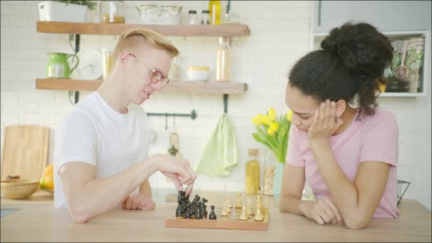 Caucasian and african american happy couple is playing chess together — Stock Video