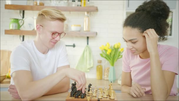 Νεαρός ξανθός άντρας παίζει σκάκι με Αφροαμερικανή νεαρή γυναίκα. — Αρχείο Βίντεο